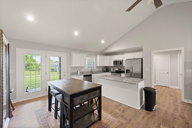 kitchen with a center island, a ceiling fan, a sink, white cabinets, and appliances with stainless steel finishes