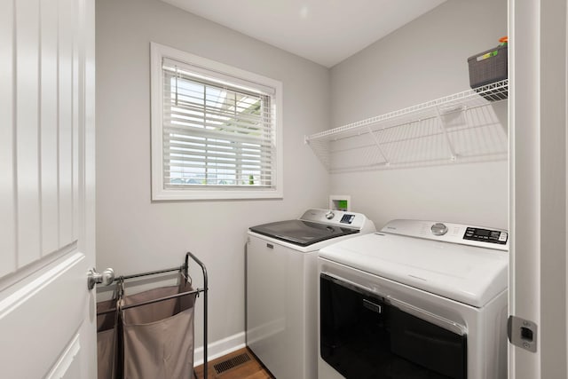 washroom with wood finished floors, laundry area, visible vents, baseboards, and independent washer and dryer