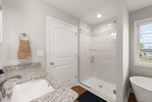 bathroom with wood finished floors, a shower stall, a freestanding tub, vanity, and recessed lighting