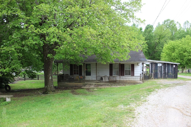single story home featuring dirt driveway, a porch, fence, and a front yard