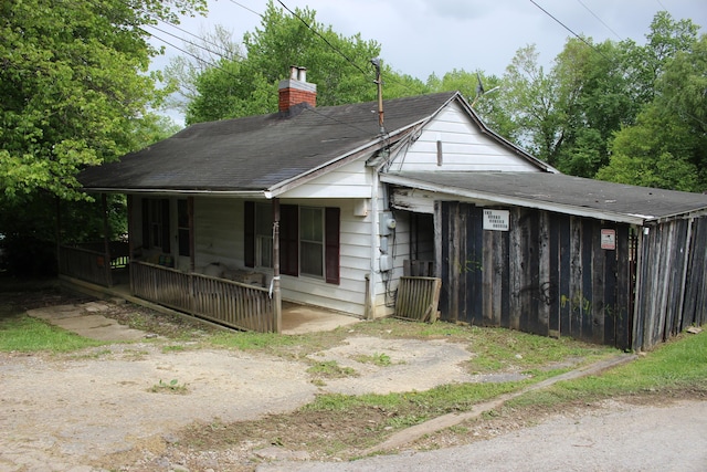 bungalow with a shingled roof, a porch, and a chimney