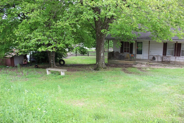 view of yard featuring covered porch and fence