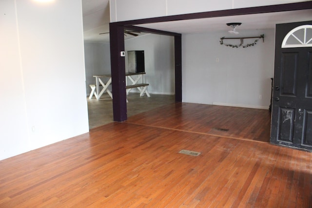 foyer entrance with beamed ceiling and wood finished floors