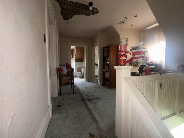 corridor with light colored carpet and an upstairs landing