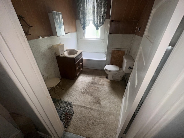 bathroom featuring toilet, a tub to relax in, and vanity
