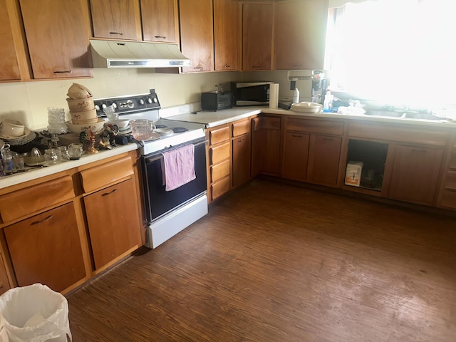 kitchen featuring electric range, under cabinet range hood, dark wood finished floors, and light countertops