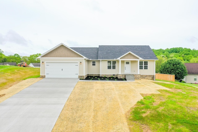 view of front of house with an attached garage, concrete driveway, a front lawn, and a shingled roof