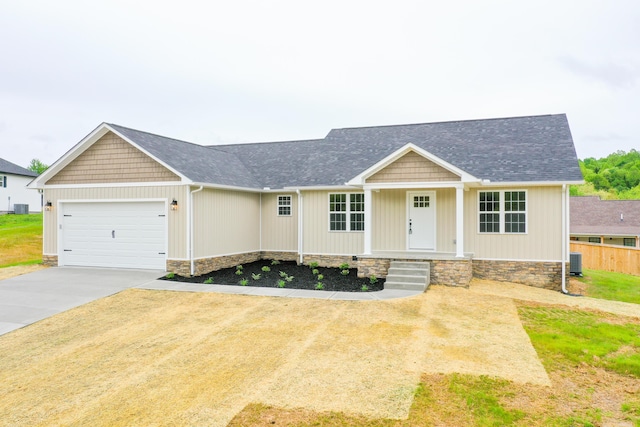 view of front of house with an attached garage, concrete driveway, central AC unit, and a shingled roof