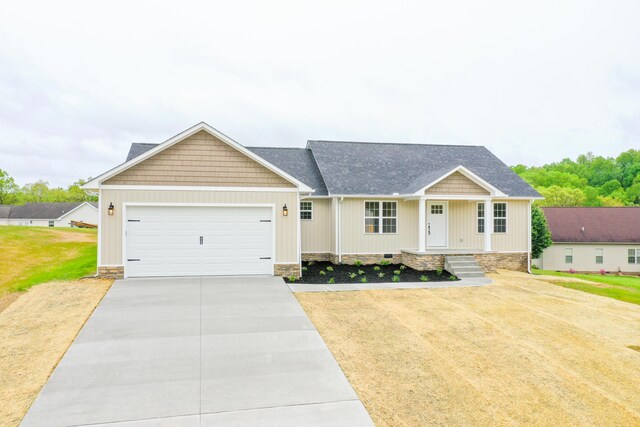 view of front facade with concrete driveway, a garage, a porch, a front lawn, and a shingled roof
