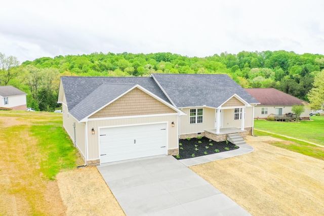ranch-style home featuring concrete driveway, a garage, a front lawn, and a wooded view