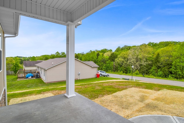 view of grassy yard with a patio and a wooded view