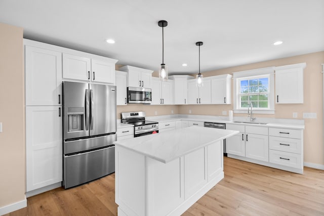 kitchen with appliances with stainless steel finishes, a sink, light wood finished floors, white cabinets, and recessed lighting