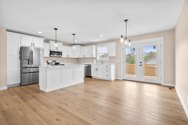 kitchen with appliances with stainless steel finishes, french doors, recessed lighting, light countertops, and a sink