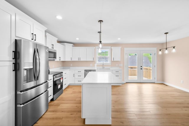 kitchen with appliances with stainless steel finishes, a sink, light countertops, white cabinetry, and light wood finished floors