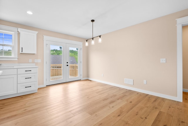 unfurnished dining area with french doors, light wood-style flooring, baseboards, and recessed lighting