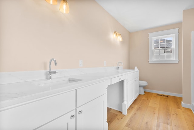 full bath featuring toilet, wood finished floors, baseboards, and double vanity