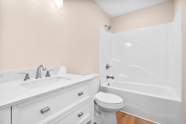 bathroom with wood finished floors, toilet, vanity, and shower / bathtub combination