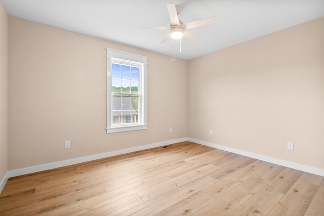 spare room with light wood-type flooring, a ceiling fan, and baseboards