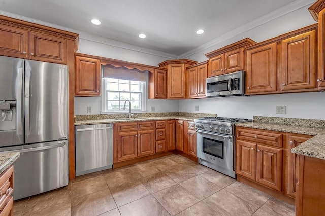 kitchen with stainless steel appliances, brown cabinets, ornamental molding, and a sink