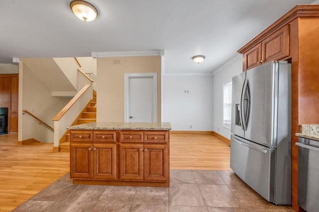 kitchen featuring brown cabinets, ornamental molding, light wood-type flooring, baseboards, and appliances with stainless steel finishes