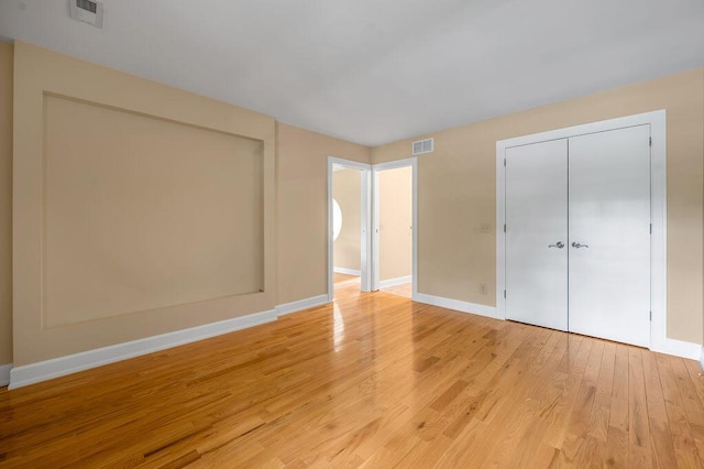 unfurnished bedroom featuring a closet, light wood-style floors, visible vents, and baseboards