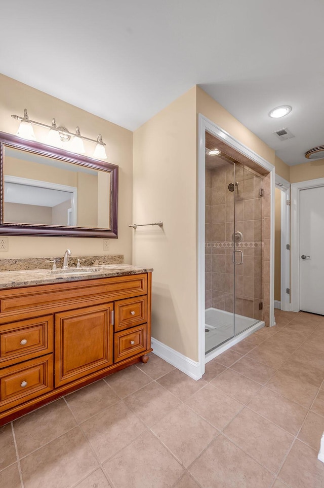 full bath featuring vanity, visible vents, tile patterned flooring, a shower stall, and baseboards