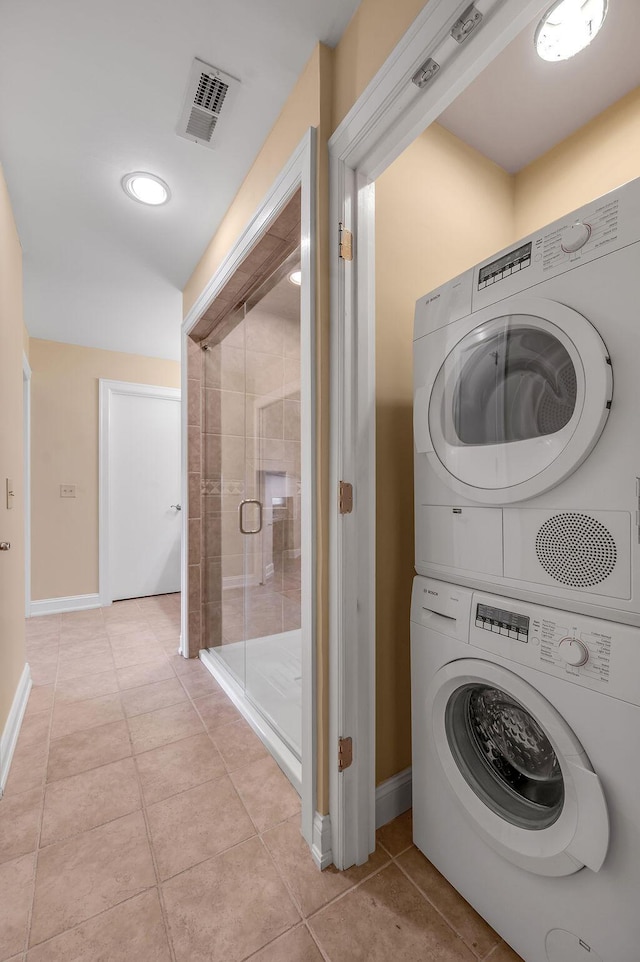 laundry room featuring stacked washer / dryer, baseboards, visible vents, light tile patterned flooring, and laundry area
