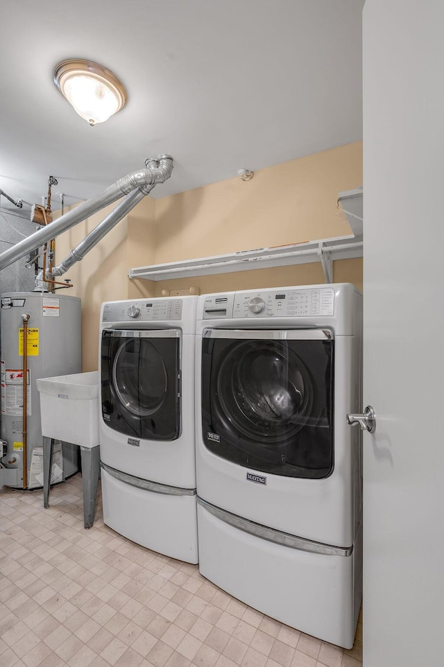 washroom featuring laundry area, water heater, and independent washer and dryer