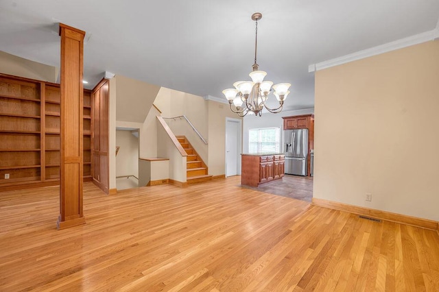 interior space with an inviting chandelier, light wood-style flooring, ornamental molding, and stairs