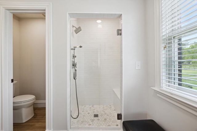 full bath with a shower stall, toilet, wood finished floors, and baseboards
