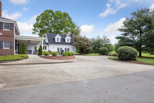 view of front of house with a chimney, a ceiling fan, and concrete driveway