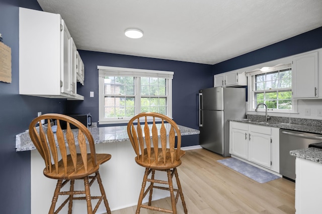 2912 Jason Ct, Lexington, KY 40503 - kitchen with stainless steel appliances, light wood-style floors, a peninsula, white cabinetry, and light stone countertops