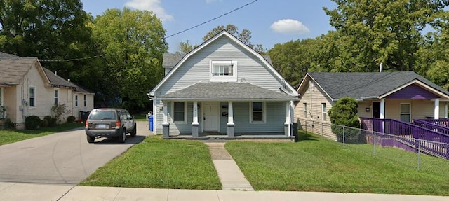 bungalow with a porch, driveway, fence, and a front yard