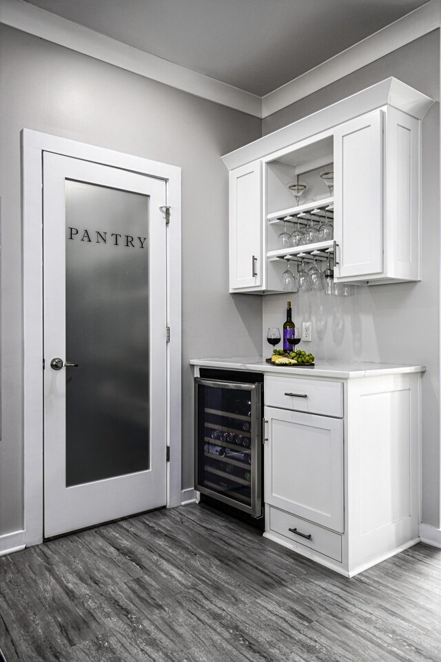 indoor dry bar with wine cooler, dark wood-style flooring, and baseboards