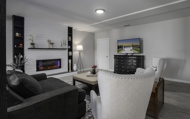 living area featuring baseboards, wood finished floors, and a fireplace