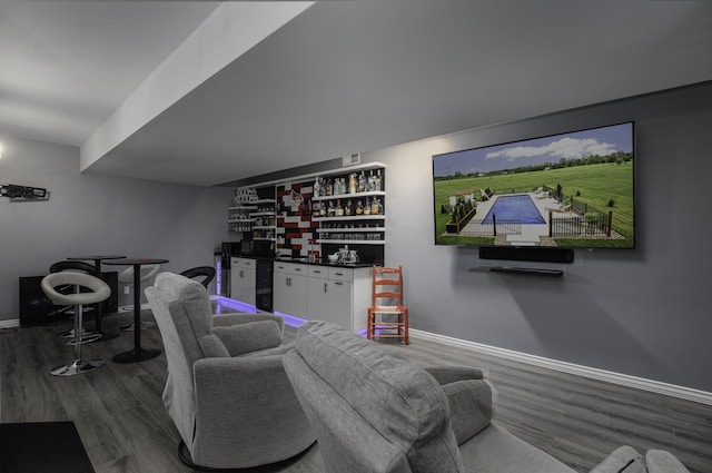 living room featuring a bar, wood finished floors, and baseboards
