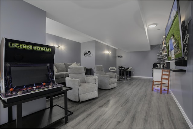 living room with wood finished floors, baseboards, and a bar
