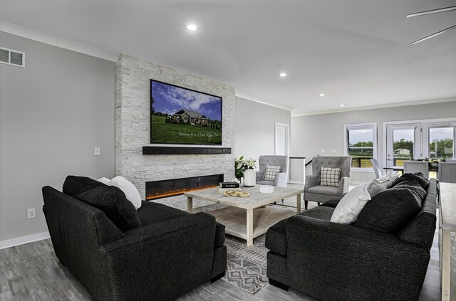living area featuring crown molding, a fireplace, wood finished floors, recessed lighting, and baseboards