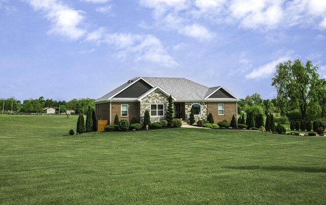 view of front of home featuring a front yard, stone siding, and brick siding
