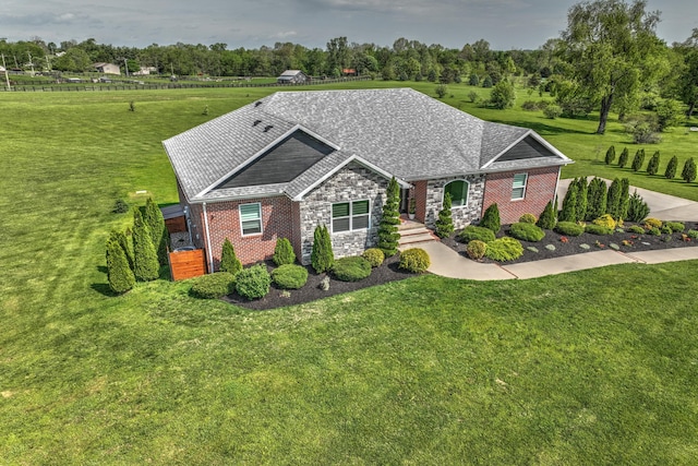 view of front of property with roof with shingles, a front yard, brick siding, and stone siding