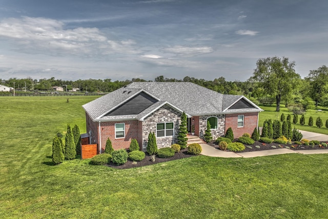 view of front of property with a front yard, stone siding, a shingled roof, and brick siding