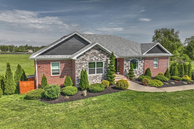 craftsman-style home with a front yard, a shingled roof, and stone siding