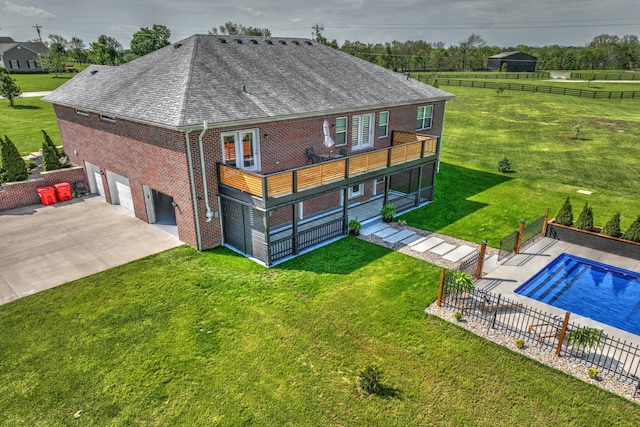rear view of house with a shingled roof, an attached garage, brick siding, concrete driveway, and an outdoor pool