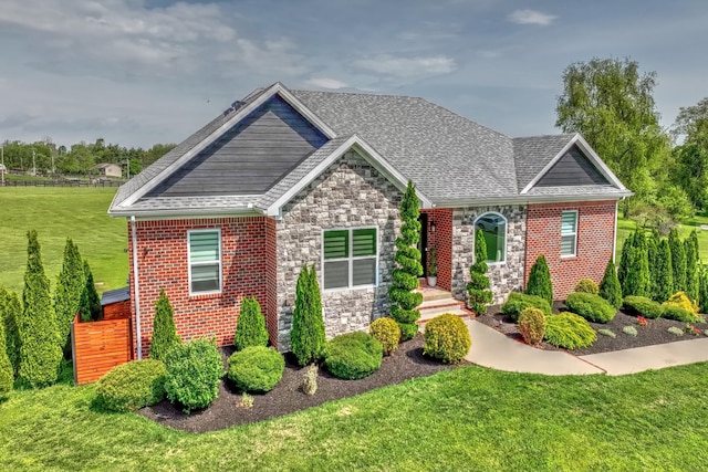 view of front of home with a front lawn, stone siding, and roof with shingles