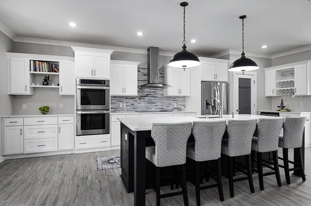 kitchen with open shelves, wall chimney exhaust hood, stainless steel appliances, ornamental molding, and a sink