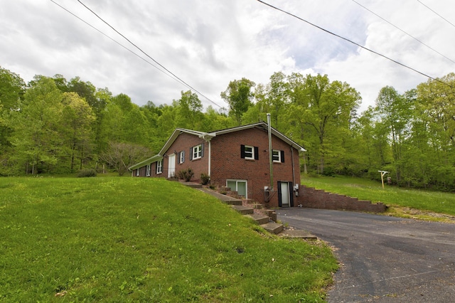 246 Pottersville Rd, Means, KY 40346 - view of side of property featuring a garage, asphalt driveway, brick siding, a yard, and a view of trees