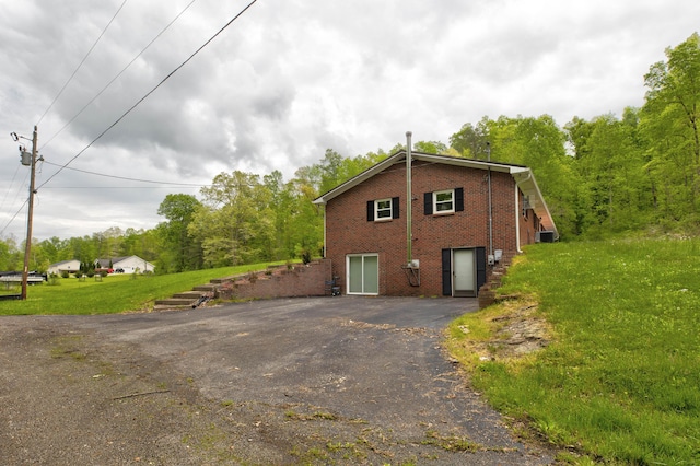 246 Pottersville Rd, Means, KY 40346 - view of home's exterior featuring brick siding, driveway, a yard, and central AC