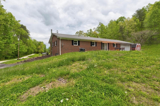 246 Pottersville Rd, Means, KY 40346 - view of front of house with brick siding, an attached garage, cooling unit, a storage unit, and an outdoor structure