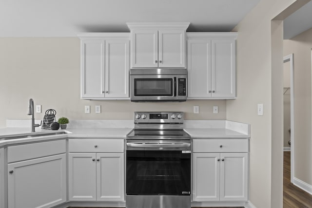 kitchen featuring appliances with stainless steel finishes, white cabinetry, a sink, and light countertops
