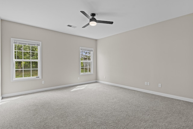 carpeted empty room featuring ceiling fan, plenty of natural light, and baseboards